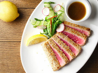 Traditional Japanese salad with medium-fried tuna Ahi slices on the grill and sesame seeds with a salad of fresh vegetables on a plate. Top view. Space for copying. Serving tuna in a restaurant. Japan