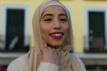 Young serene female in traditional hijab looking at you
