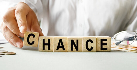 CHANCE inscription on the texture of wooden cubes. A business man holds a cube in his hand. An inscription on a financial, business or economic theme.