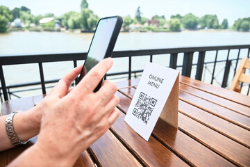 Hands of an unrecognizable woman scanning a QR code to access a restaurant menu