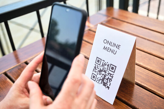 Hands of an unrecognizable woman scanning a QR code to access a restaurant menu