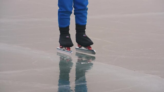 The child train on ice speed skating. The legs in skates close up. The kid girl skates in the winter in sportswear, sport glasses. Children speed skating short long track. Outdoor slow motion.