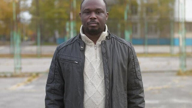 Afro-american man from Nigeria stands on sport ground and look at the camera