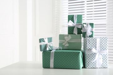 Heap of wrapped gift boxes on white table, space for text. Happy holiday