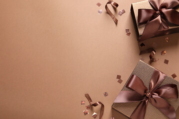 Beautiful gift boxes and confetti on brown background, flat lay. Space for text