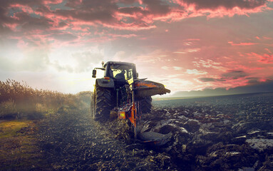 Tractor on the field during sunset. - obrazy, fototapety, plakaty