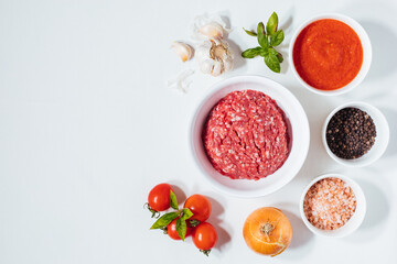 Meatballs in tomato sauce with basil on top. Bright background with ingredients in blurry background. This meal is called Kofte in Turkey and Cufte in Balkans. International meatball day.