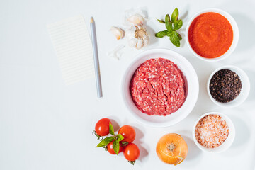 Meatballs in tomato sauce with basil on top. Bright background with ingredients in blurry background. This meal is called Kofte in Turkey and Cufte in Balkans. International meatball day.