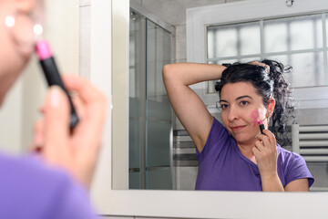 Woman in front of a mirror paints the female sign on her face with lipstick. Concept of feminist.