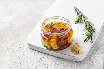 Composition with nature feta cheese in glass jar and rosemary on white board