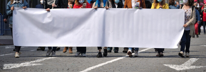 Grupo de pessoas numa manifestação de rua a segurar uma tela em branco - colocar mensagem - sexo feminino - setas no pavimento da estrada  - obrazy, fototapety, plakaty