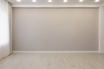 Empty room with beige wall, large window and wooden floor