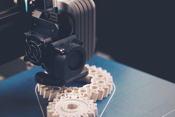 matte scenery of FDM-3D-printer with blue print platform that manufactures white helical gears from...
