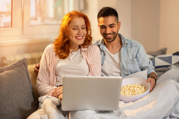 Beautiful couple watching movie on laptop at home