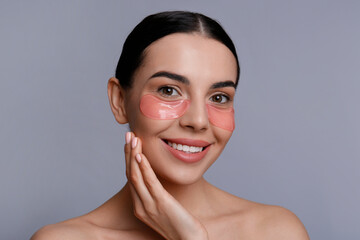 Beautiful young woman with under eye patches on grey background © New Africa