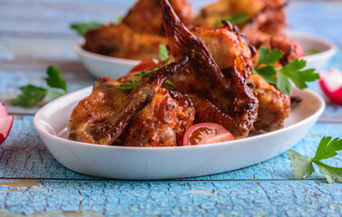 Baked crispy chicken wings in a white plate on a blue background