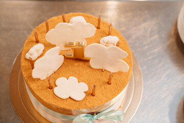 a small cake decorated with ribbons and sugar clouds with candles