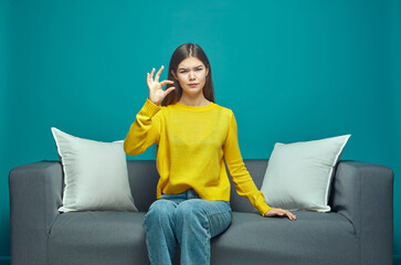 Displeased young girl showing little bit gesture, small size, dissatisfied with low rating, sitting on couch