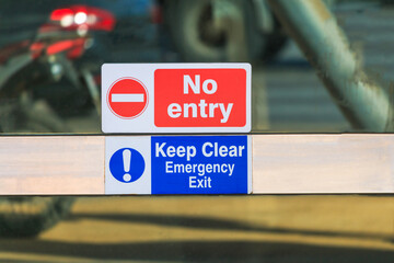 Sign on door NO ENTRY, KEEP CLEAR EMERGENCY EXIT, reflection on glass