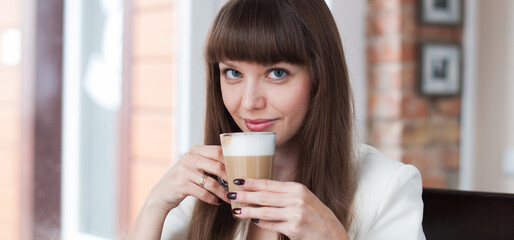 Stylish young woman drinking coffee at the cafe - 486974188
