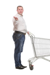 Full length side view of handsome young man standing with shopping trolley and looking at camera