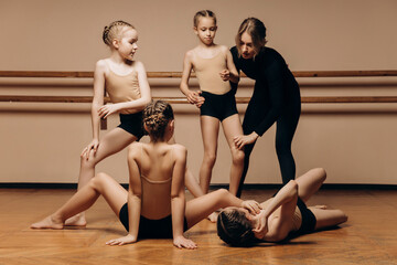 Full-length portrait of a beautiful dance teacher instructing a group of little girls in a dance studio, a space for copying