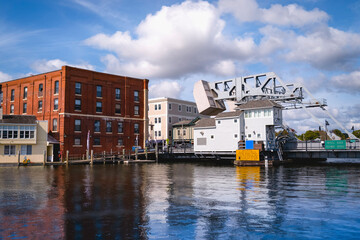 Naklejka premium Mystic drawbridge, redbrick building, water reflections, and cloudscape