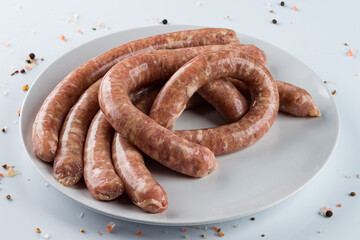 Raw Chicken Sausages with spices, close-up on white background.