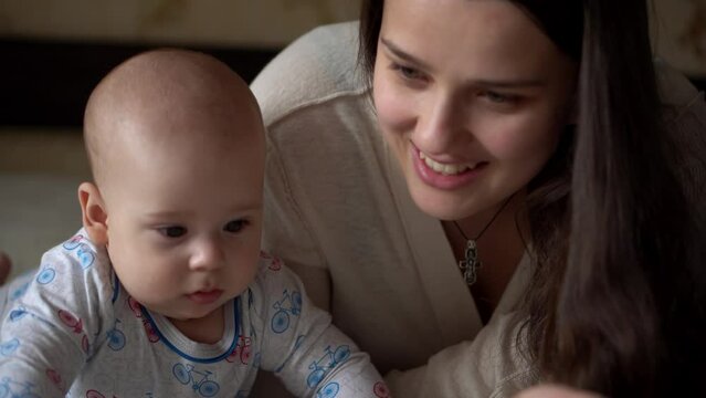Newborn Active Baby With Young Mom. Cute Smiling Teethless Face Portrait Early Days On Stomach Developing Neck Control. Woman With Child Look At Camera Reed Book. Infant, Childbirth, Beginning Concept