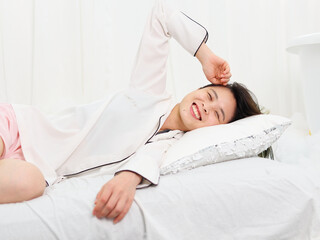 Portrait of young Asian woman lying and smiling on bed isolated on white background, beautiful Chinese girl with green hairs in white shirt grinning on bed. 
