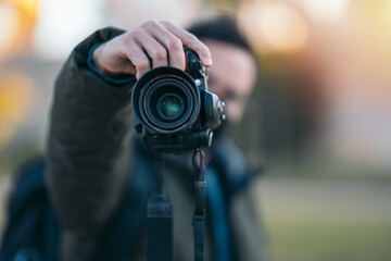 Soft focus of male photographer hold camera and taking a photo on nature. Shallow depth of field. 50mm