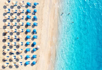 Foto op Aluminium Luchtfoto strand Luchtfoto van blauwe zee, zandstrand met ligbedden en parasols bij zonsondergang in de zomer. Tropisch landschap met turkoois water, mensen, ligstoel. Reizen en vakantie. Lefkas eiland, Griekenland. Bovenaanzicht