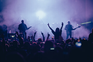 Silhouette of a woman with raised hands on a concert