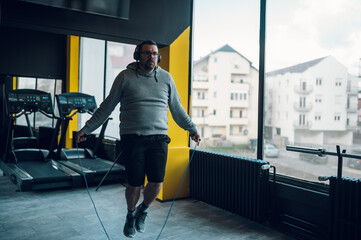 Middle aged man training in the gym with jump rope - obrazy, fototapety, plakaty
