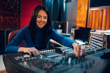 Woman music producer working on a mixing soundboard in a studio.