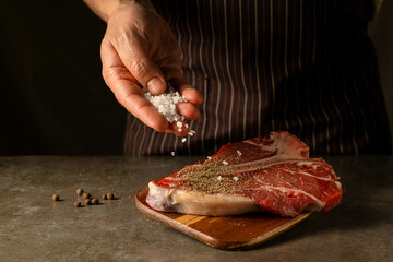 Raw T-bone steak with coarse salt and black pepper