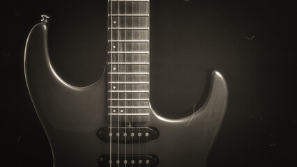 Fototapeta premium A vintage black and white electric guitar standing upright on textured noir concept as wallpaper. Music concept