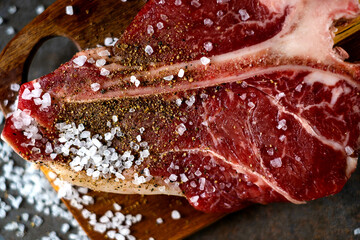 Raw T-bone steak cooking on stone table