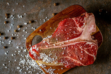 Raw T-bone steak cooking on stone table