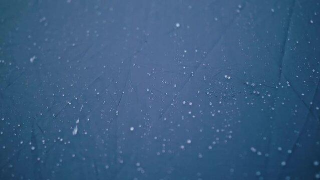 Close-up shot of raindrops water droplets on the tent. Dew drops on texture of fabric of tourist tent in rays of rising or setting sun. Camp, hiking tourism. The rain is pounding on tent. Slow motion