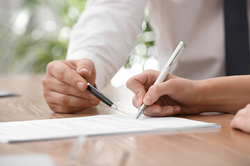 Businesspeople signing contract at table in office, closeup