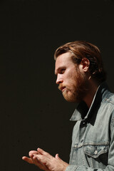 Headshot of thoughtful bearded man posing outdoor wears denim jacket. Vertical.