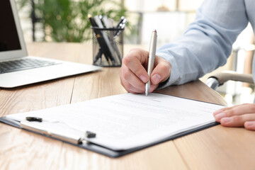 Man signing contract at table in office, closeup.