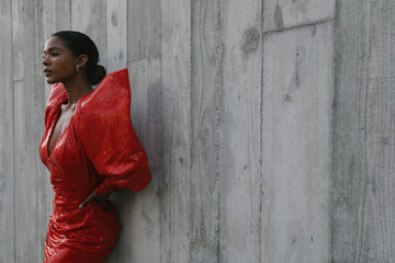 Gorgeous African American woman wears a red cocktail dress. Posing outdoor.