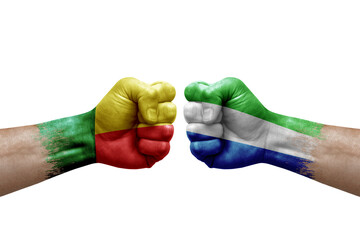 Two hands punch to each others on white background. Country flags painted fists, conflict crisis concept between benin and sierra leone