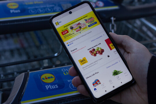 Mysłowice, Poland &ndash; February 12, 2022: A man in scrolling through Lidl Plus app while shopping at Lidl. 