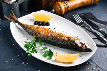 Baked mackerel stuffed with herbs, served with parsley on a white plate. Concept of a healthy homemade food.