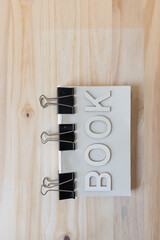 the word "book" on a blank text block with metal clips 