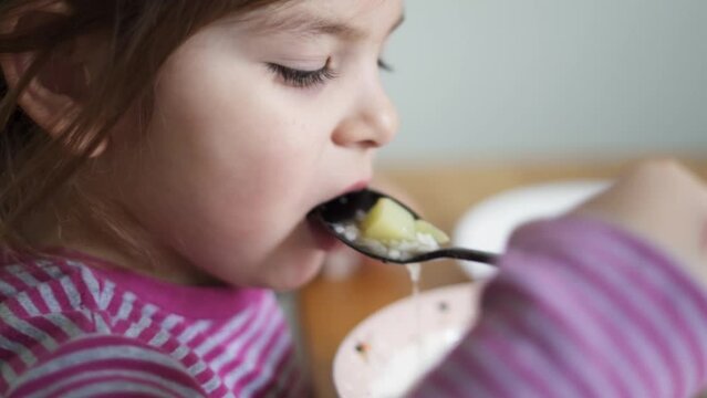 Close up of preschool girl portrait with eating soup at home. picky eater 