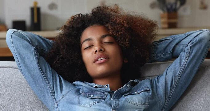 Close up of beautiful carefree African teenage girl relaxing alone at home, breath fresh-conditioned air inside modern domestic room, enjoy silent household appliances, take break, no stress concept